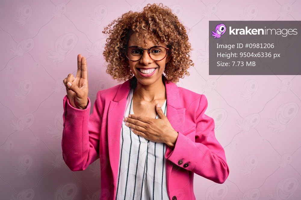 Young african american businesswoman wearing glasses standing over pink background smiling swearing with hand on chest and fingers up, making a loyalty promise oath