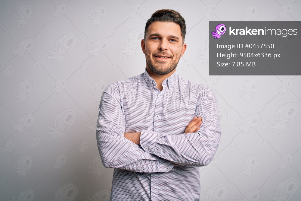 Young business man with blue eyes standing over isolated background happy face smiling with crossed arms looking at the camera. Positive person.