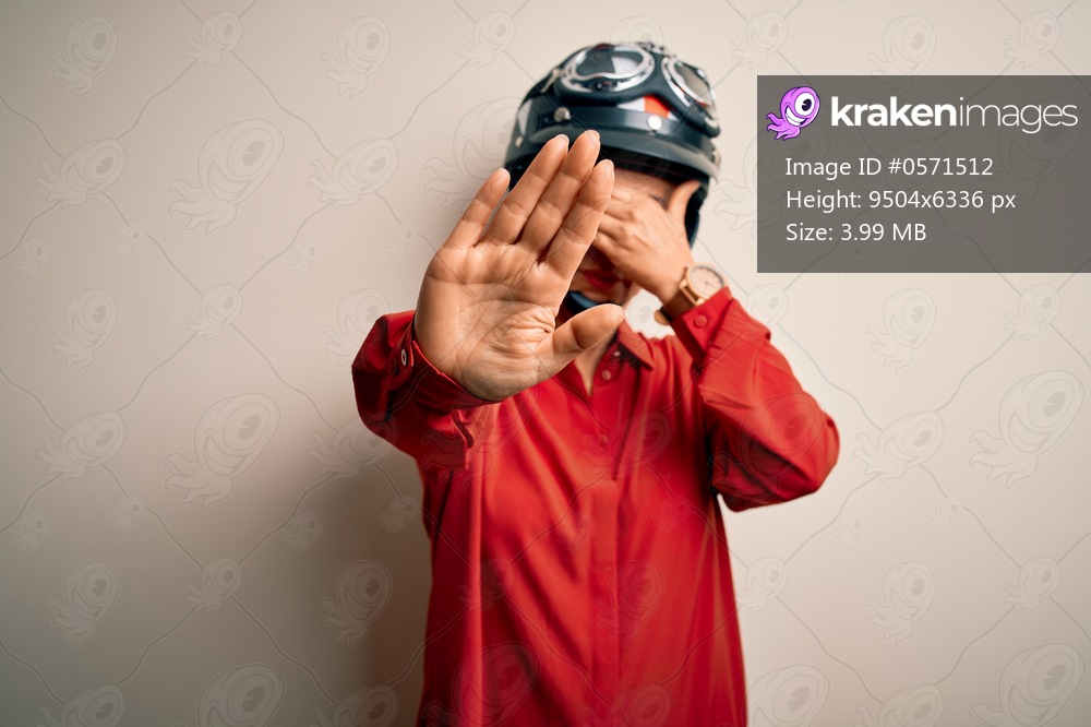 Middle age motorcyclist woman wearing motorcycle helmet over isolated white background covering eyes with hands and doing stop gesture with sad and fear expression. Embarrassed and negative concept.