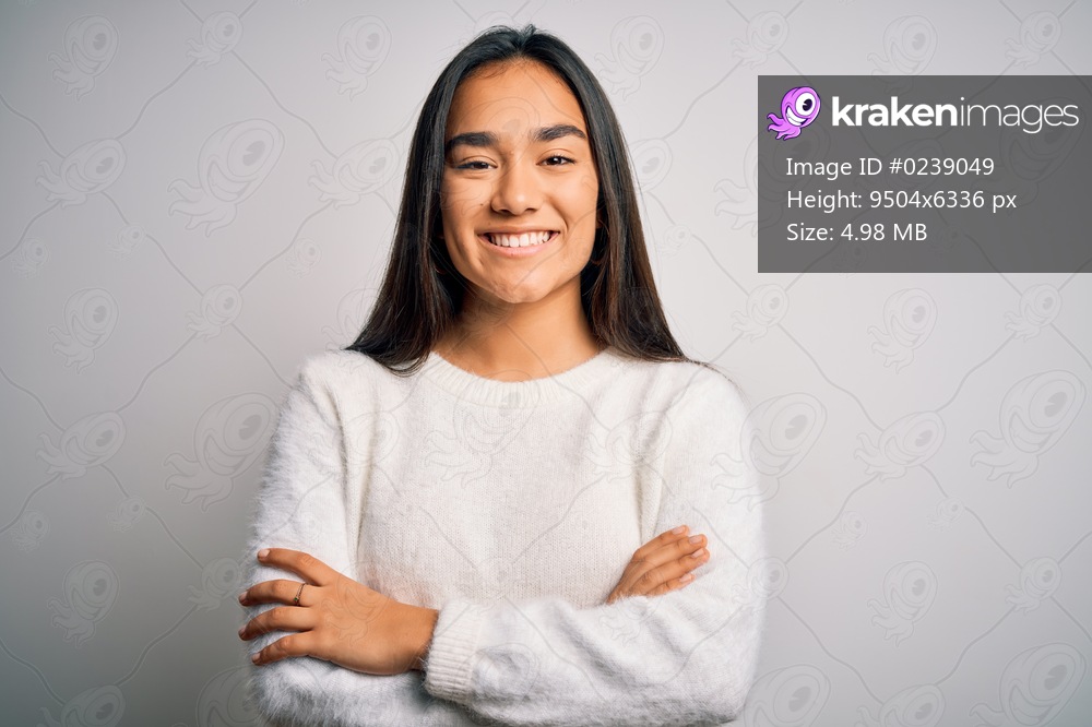 Young beautiful asian woman wearing casual sweater standing over white background happy face smiling with crossed arms looking at the camera. Positive person.