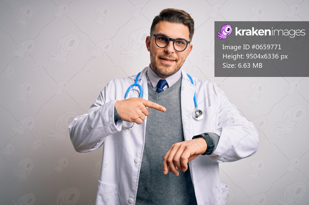Young doctor man with blue eyes wearing medical coat and stethoscope over isolated background In hurry pointing to watch time, impatience, upset and angry for deadline delay