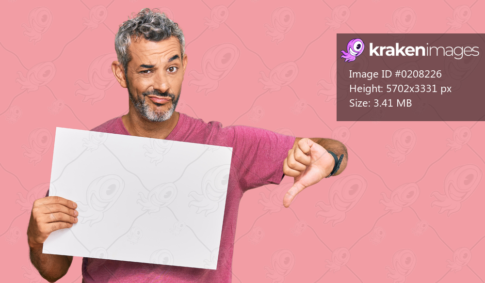 Middle age grey-haired man holding blank empty banner with angry face, negative sign showing dislike with thumbs down, rejection concept 