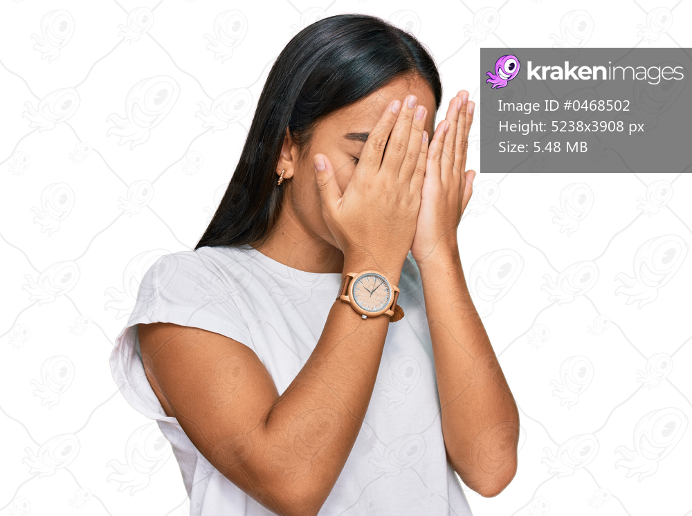 Young asian woman wearing casual white t shirt with sad expression covering face with hands while crying. depression concept. 