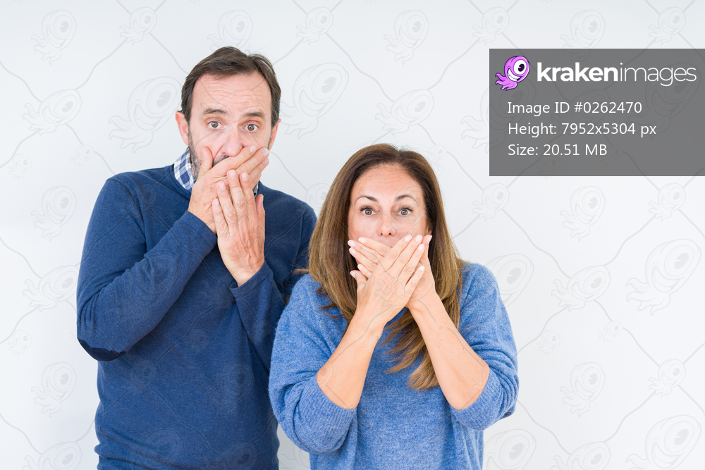 Beautiful middle age couple in love over isolated background shocked covering mouth with hands for mistake. Secret concept.