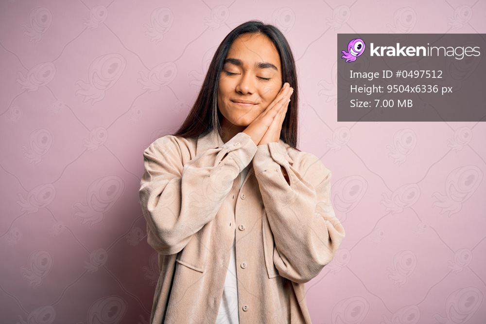 Young beautiful asian woman wearing casual shirt standing over pink background sleeping tired dreaming and posing with hands together while smiling with closed eyes.