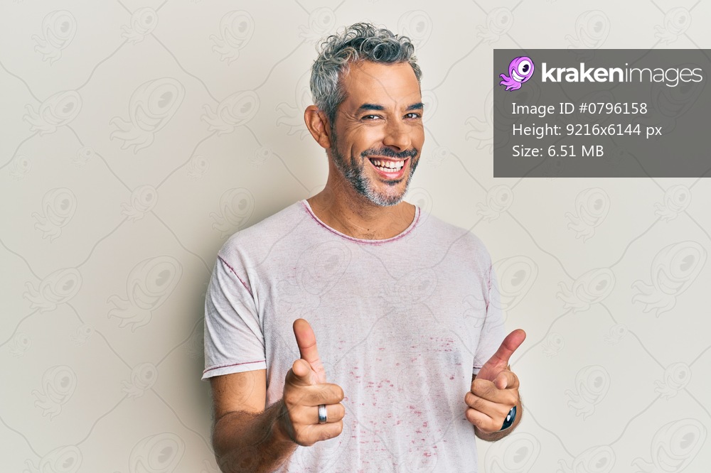 Middle age grey-haired man wearing casual clothes pointing fingers to camera with happy and funny face. good energy and vibes. 