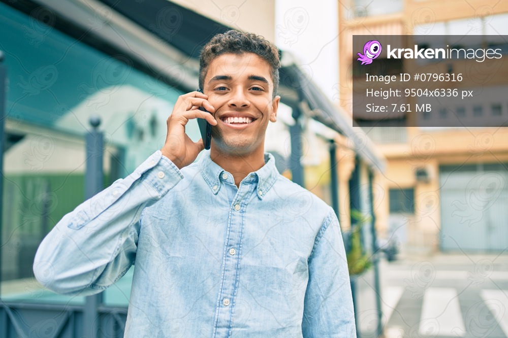 Young latin man smiling happy talking on the smartphone walking at the city.