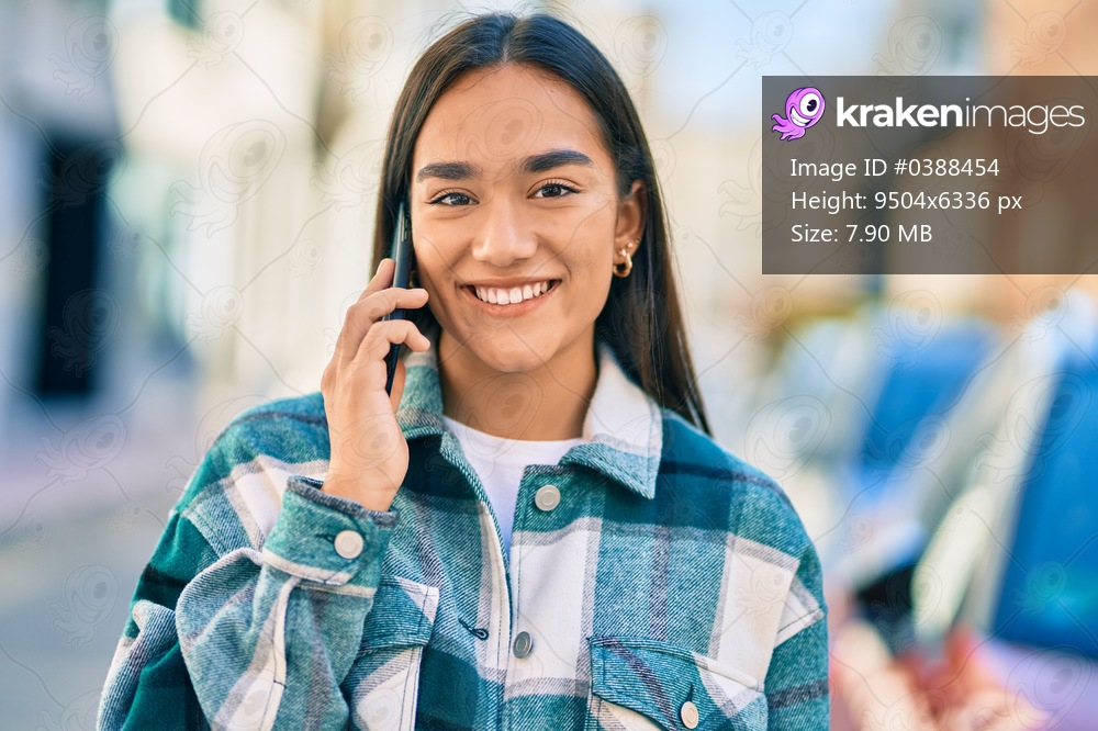 Young latin girl smiling happy talking on the smartphone at the city.