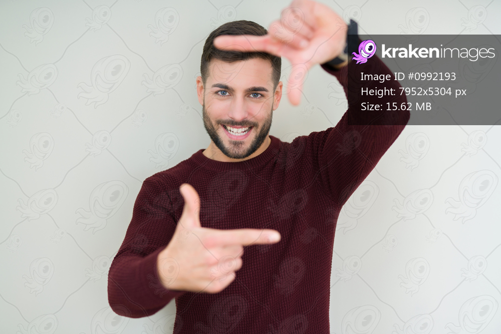 Young handsome man wearing a sweater over isolated background smiling making frame with hands and fingers with happy face. Creativity and photography concept.