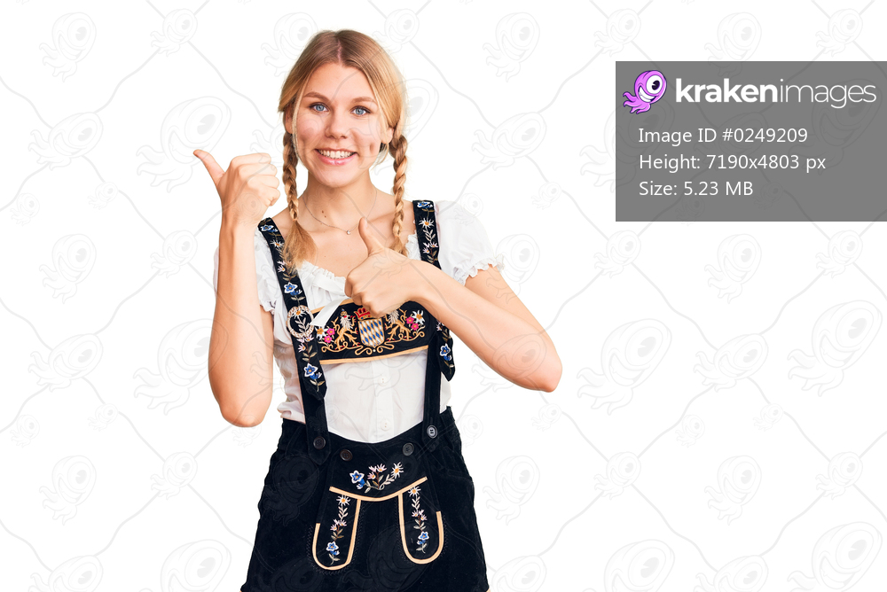 Young beautiful blonde woman wearing oktoberfest dress pointing to the back behind with hand and thumbs up, smiling confident 