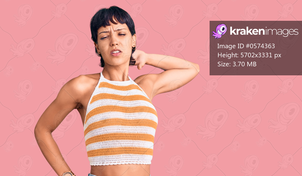 Young brunette woman with short hair wearing casual clothes suffering of neck ache injury, touching neck with hand, muscular pain 