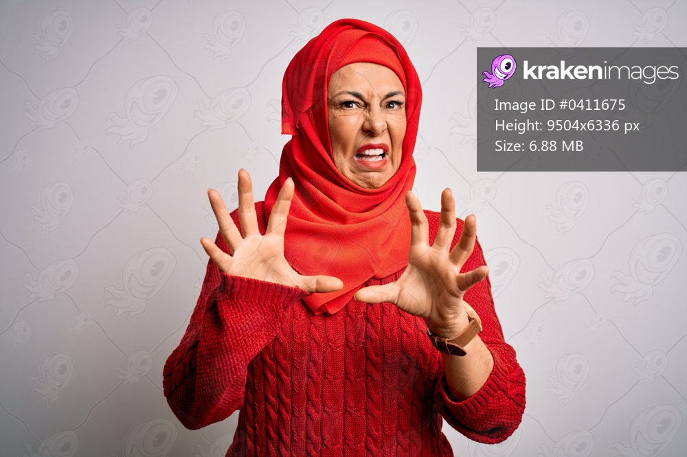 Middle age brunette woman wearing muslim traditional hijab over isolated white background afraid and terrified with fear expression stop gesture with hands, shouting in shock. Panic concept.