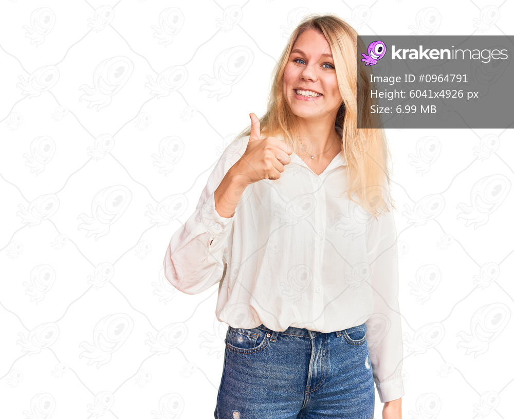Young beautiful blonde woman wearing casual shirt smiling happy doing ok sign with hand on eye looking through fingers 
