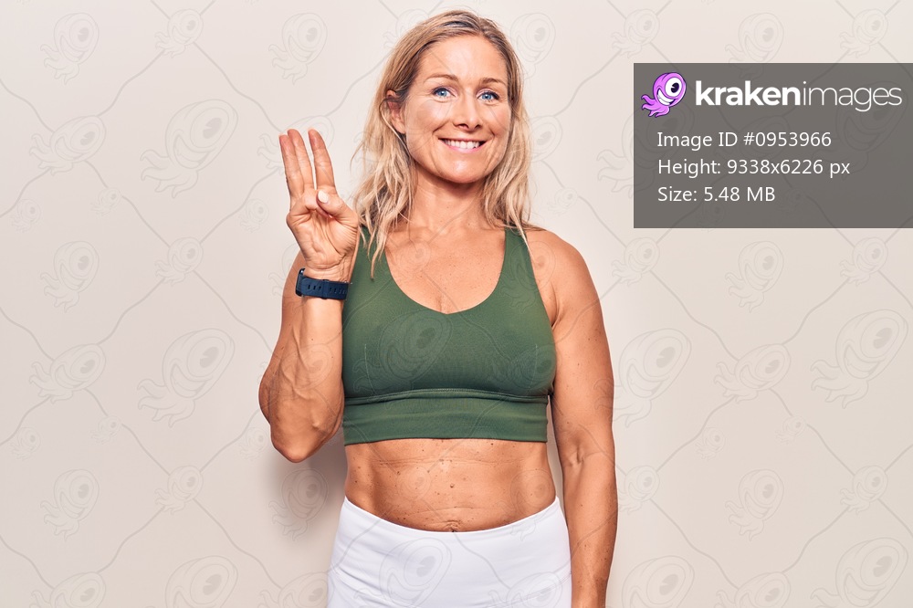 Middle age caucasian blonde woman wearing sportswear showing and pointing up with fingers number three while smiling confident and happy. 