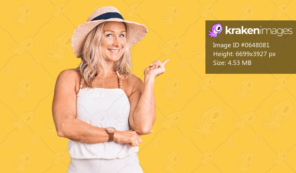 Middle age fit blonde woman wearing summer hat with a big smile on face, pointing with hand and finger to the side looking at the camera. 