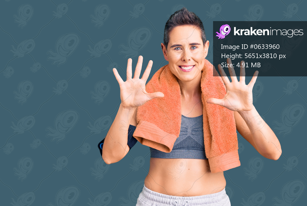 Young woman with short hair wearing sportswear and towel using smartphone showing and pointing up with fingers number ten while smiling confident and happy. 