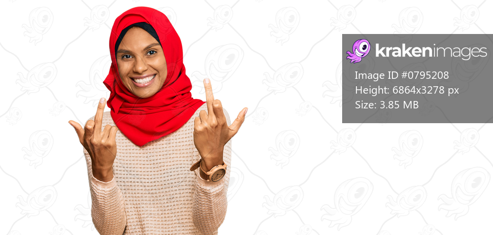 Young african american woman wearing traditional islamic hijab scarf showing middle finger doing fuck you bad expression, provocation and rude attitude. screaming excited 