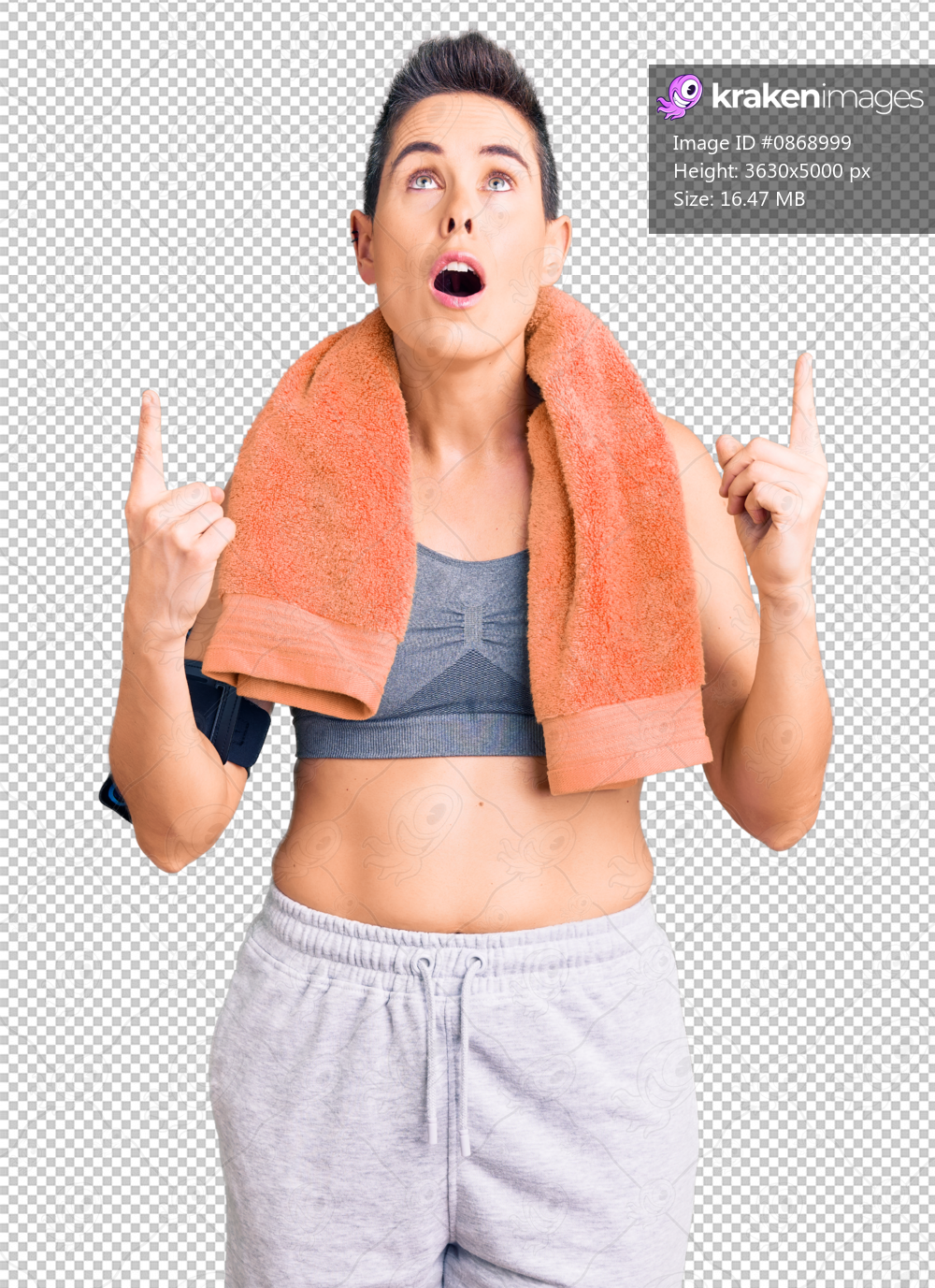 Young woman with short hair wearing sportswear and towel using smartphone amazed and surprised looking up and pointing with fingers and raised arms.
