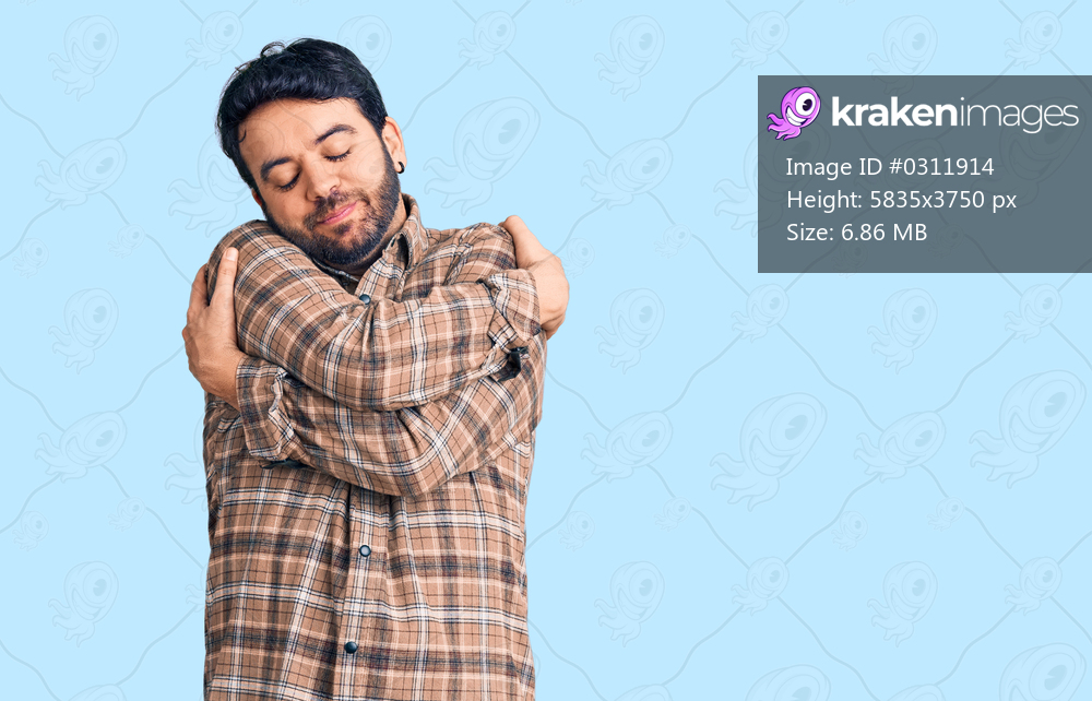 Young hispanic man wearing casual clothes hugging oneself happy and positive, smiling confident. self love and self care 