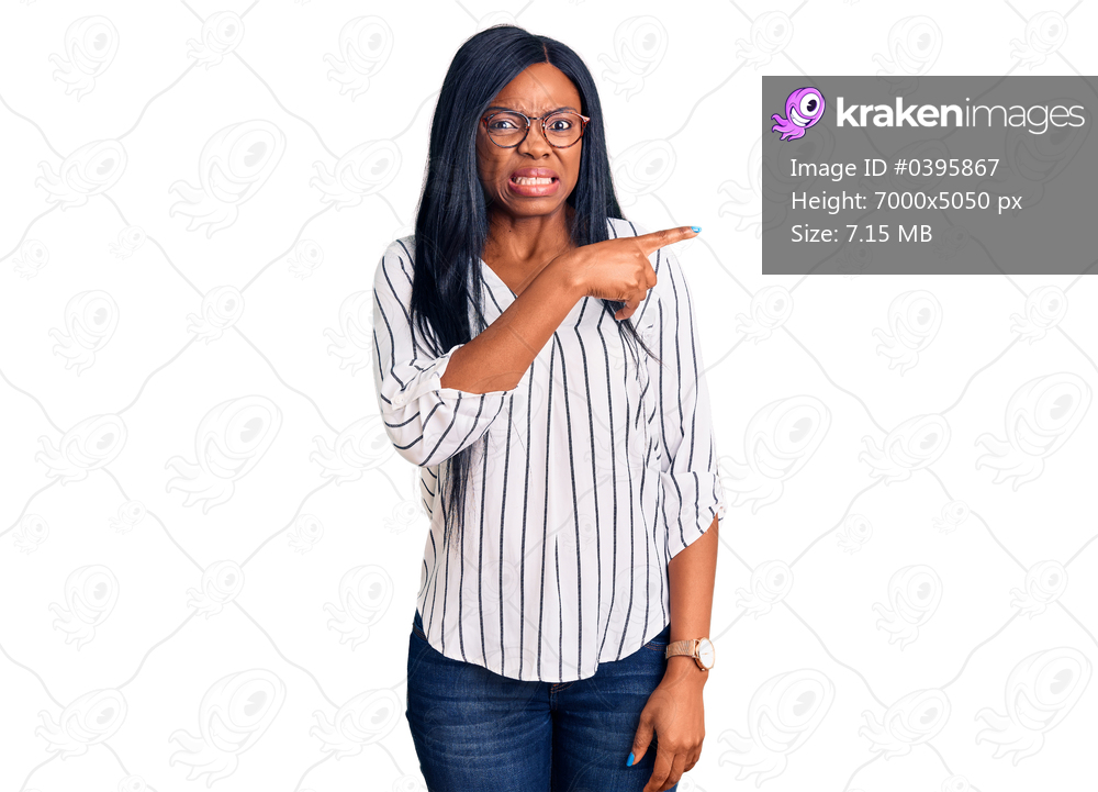 Young african american woman wearing casual clothes and glasses pointing aside worried and nervous with forefinger, concerned and surprised expression 