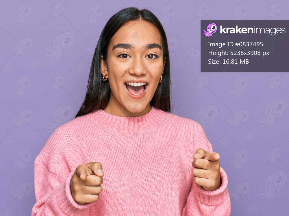 Young asian woman wearing casual winter sweater pointing fingers to camera with happy and funny face. good energy and vibes. 