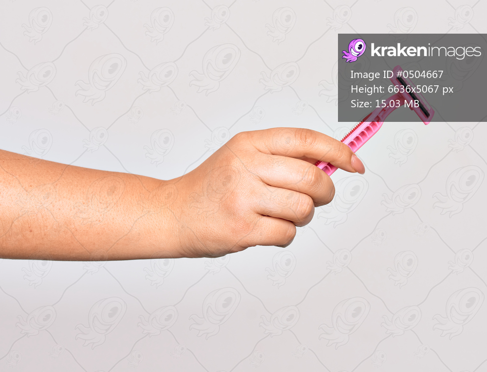 Hand of caucasian young woman holding pink razor over isolated white background