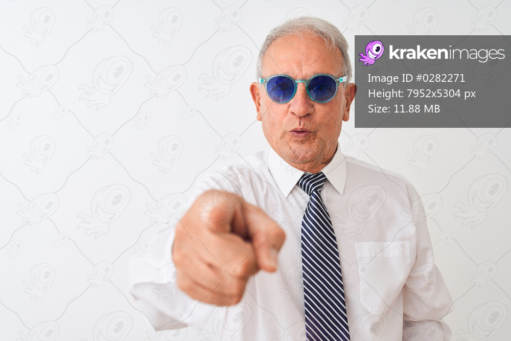 Senior grey-haired businessman wearing tie and sunglasses over isolated white background pointing with finger to the camera and to you, hand sign, positive and confident gesture from the front
