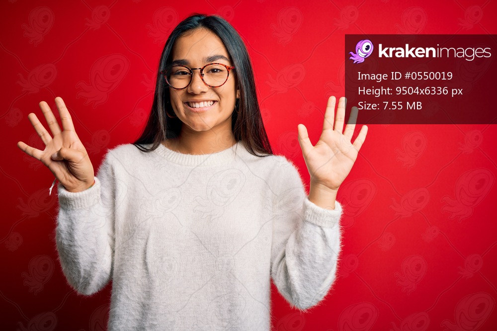 Young beautiful asian woman wearing casual sweater and glasses over red background showing and pointing up with fingers number nine while smiling confident and happy.
