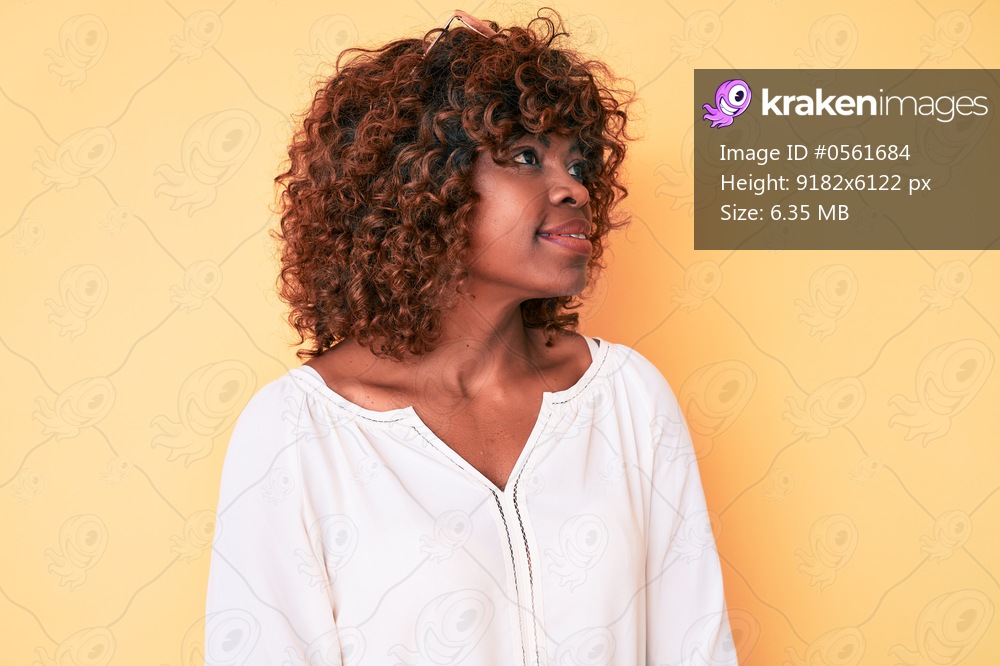 Young african american woman wearing casual clothes looking away to side with smile on face, natural expression. laughing confident. 