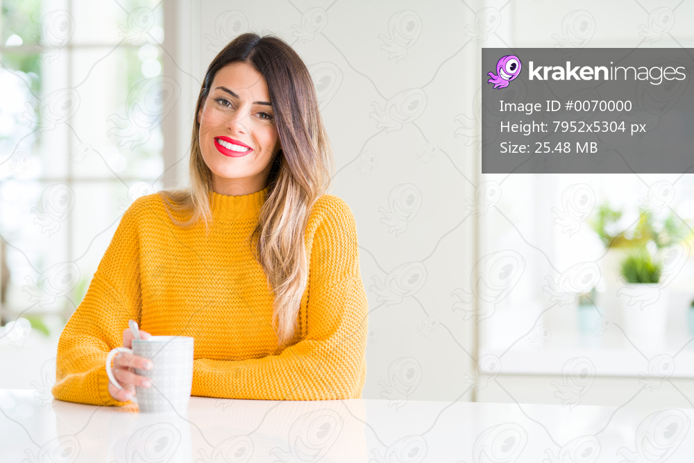 Young beautiful woman drinking a cup of coffee at home with a happy face standing and smiling with a confident smile showing teeth