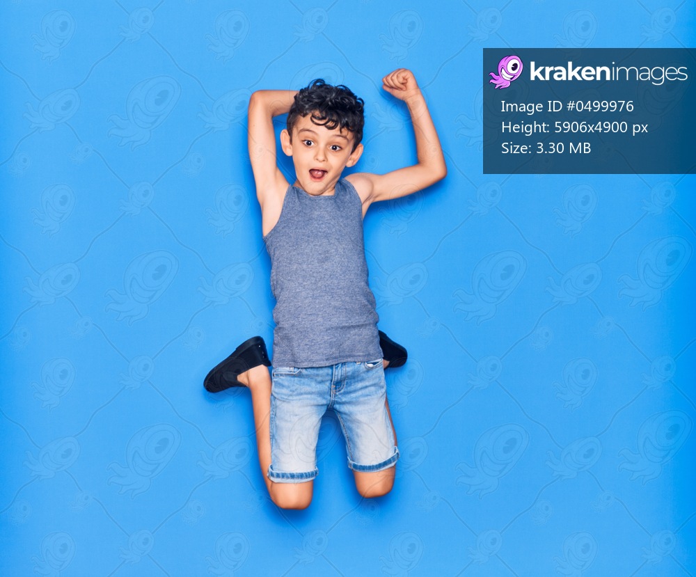 Adorable kid wearing casual clothes jumping over isolated blue background