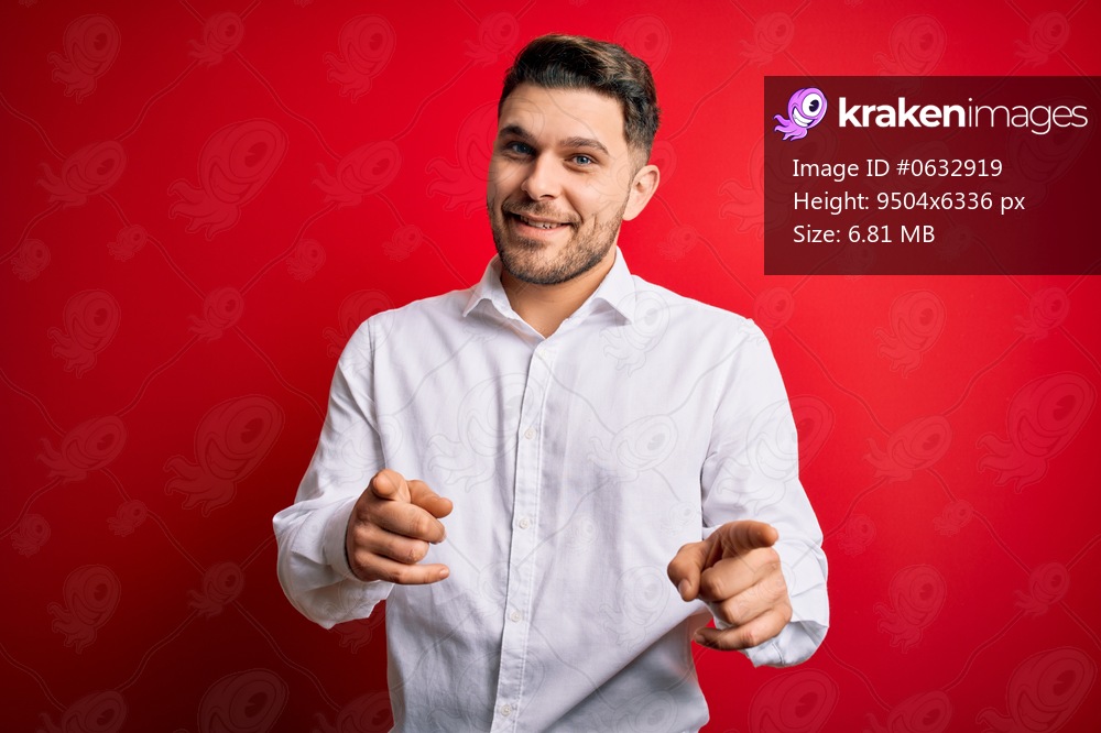 Young business man with blue eyes wearing elegant shirt standing over red isolated background pointing fingers to camera with happy and funny face. Good energy and vibes.