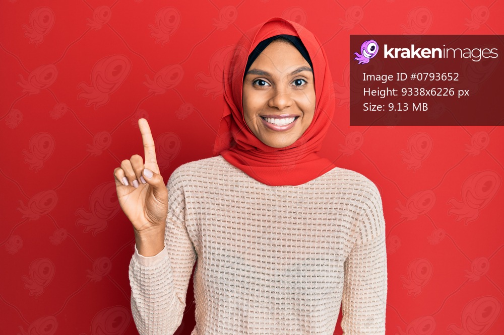 Young african american woman wearing traditional islamic hijab scarf smiling with an idea or question pointing finger up with happy face, number one 
