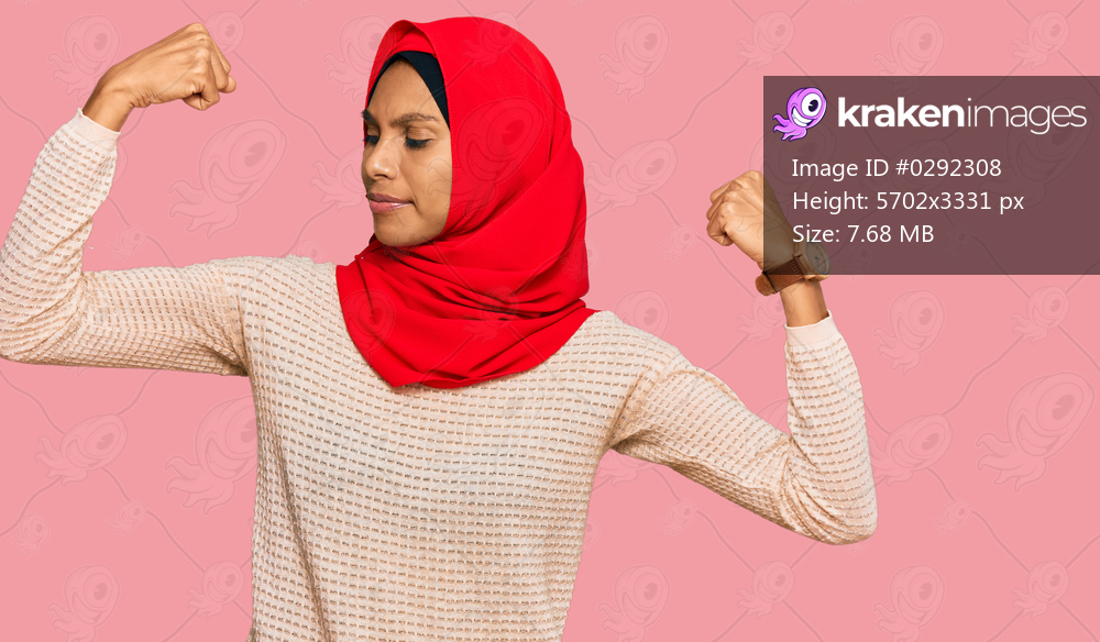 Young african american woman wearing traditional islamic hijab scarf showing arms muscles smiling proud. fitness concept. 