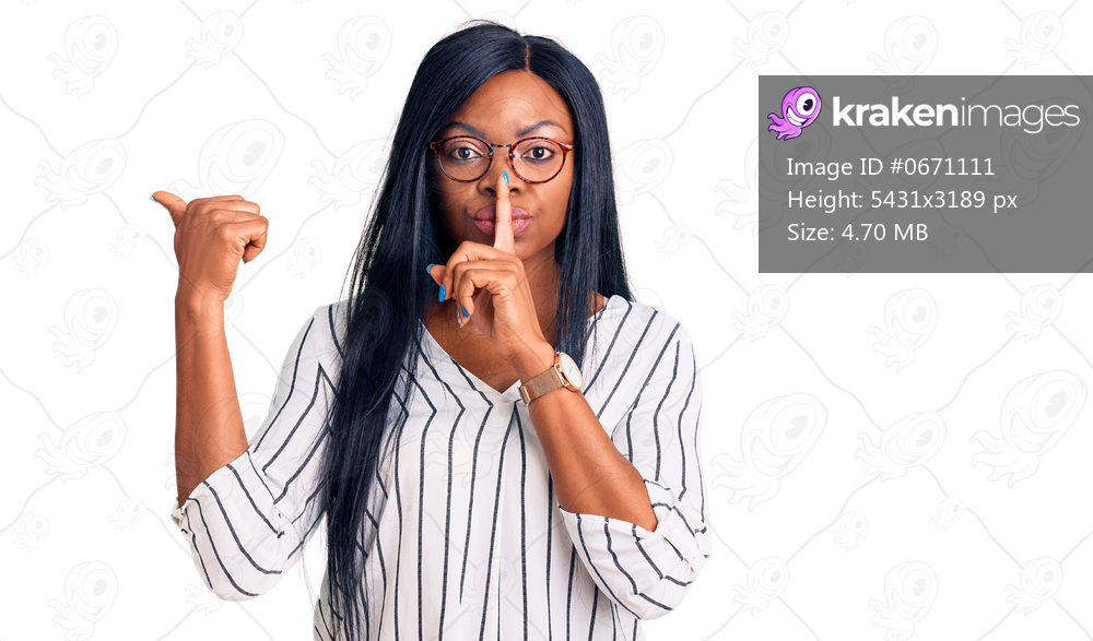 Young african american woman wearing casual clothes and glasses asking to be quiet with finger on lips pointing with hand to the side. silence and secret concept. 
