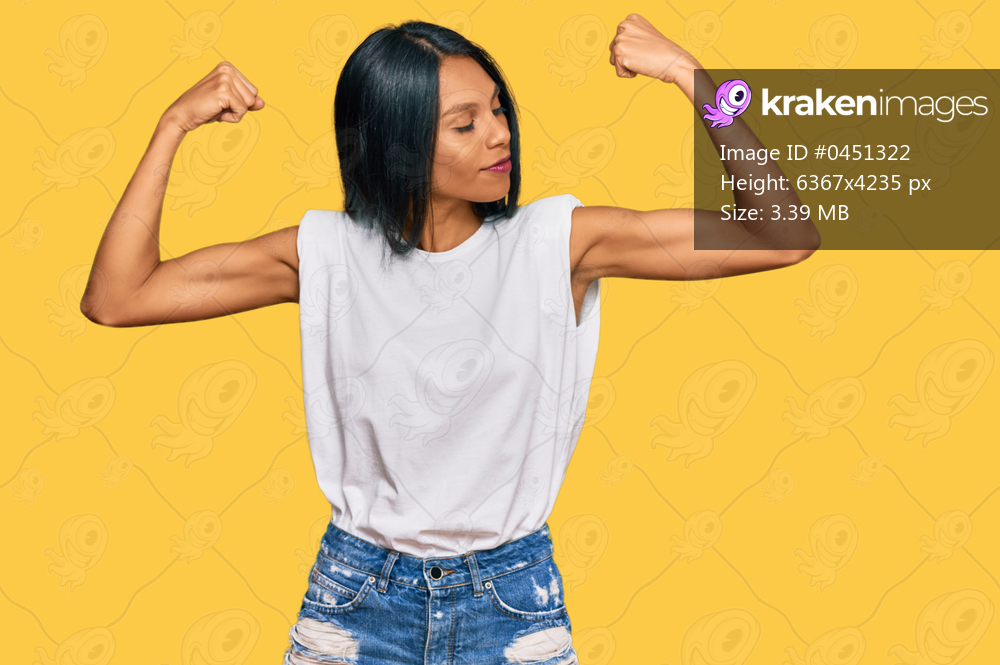 Young african american woman wearing casual clothes showing arms muscles smiling proud. fitness concept. 