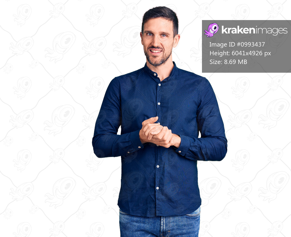 Young handsome man wearing casual shirt with hands together and crossed fingers smiling relaxed and cheerful. success and optimistic 