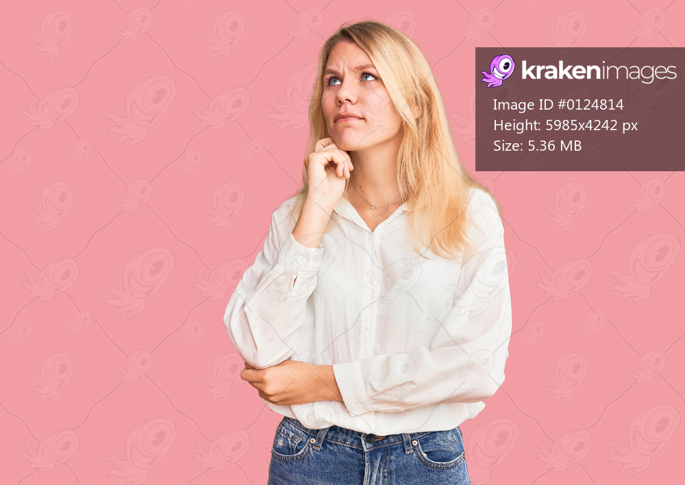 Young beautiful blonde woman wearing casual shirt serious face thinking about question with hand on chin, thoughtful about confusing idea 