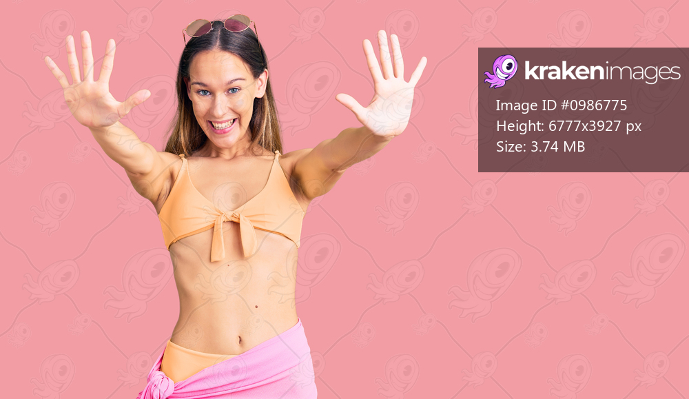 Beautiful brunette young woman wearing bikini and sunglasses showing and pointing up with fingers number ten while smiling confident and happy. 