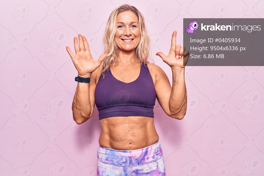 Middle age caucasian blonde woman wearing sportswear over pink background showing and pointing up with fingers number seven while smiling confident and happy. 