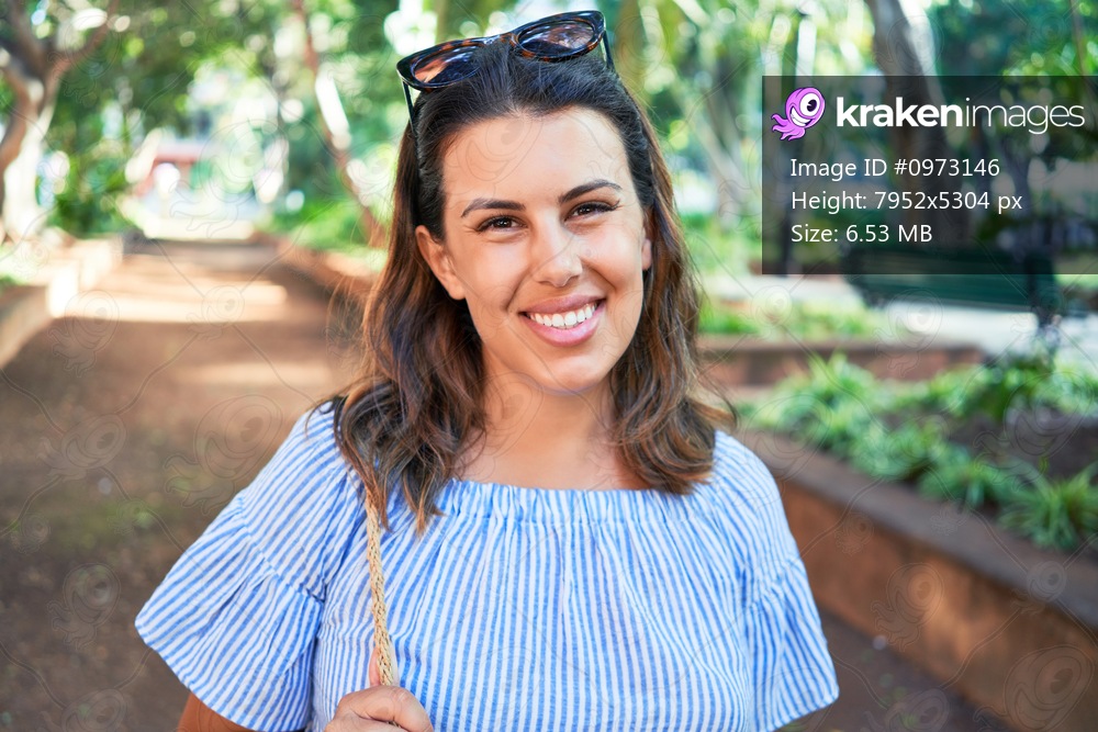 Young beatiful woman smiling happy and cheerful at green park on a sunny day of summer
