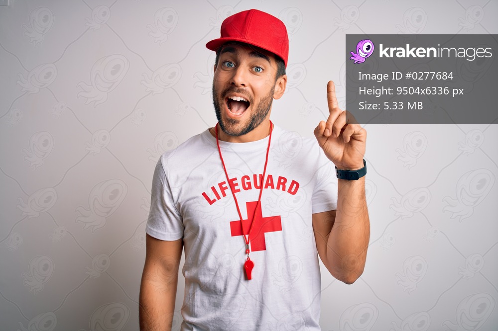 Young handsome lifeguard man with beard wearing t-shirt with red cross and whistle pointing finger up with successful idea. Exited and happy. Number one.