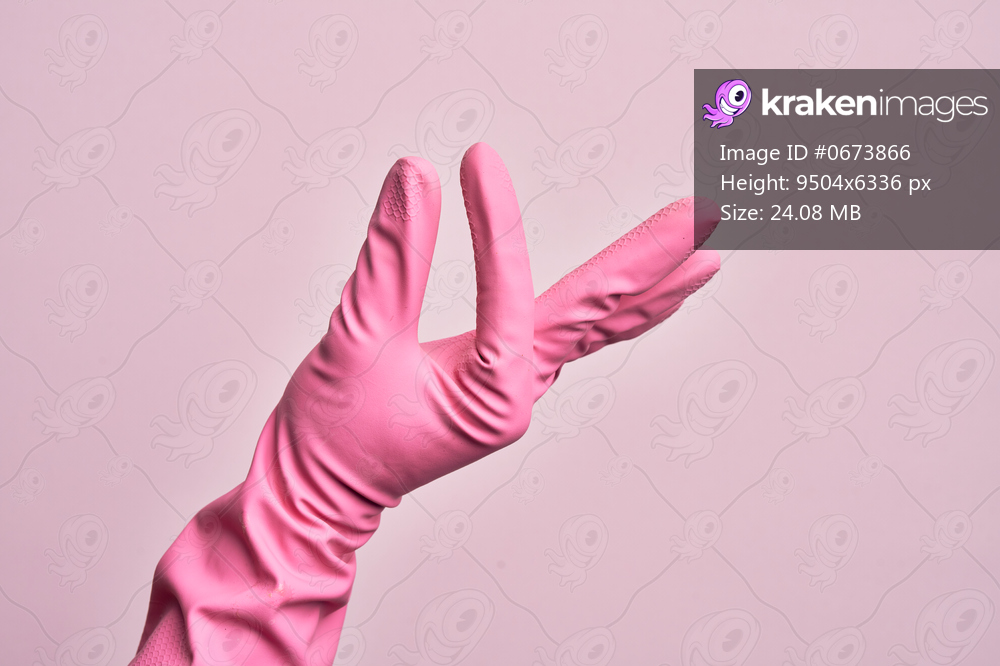 Hand of caucasian young man with cleaning glove over isolated pink background picking and taking invisible thing, holding object with fingers showing space