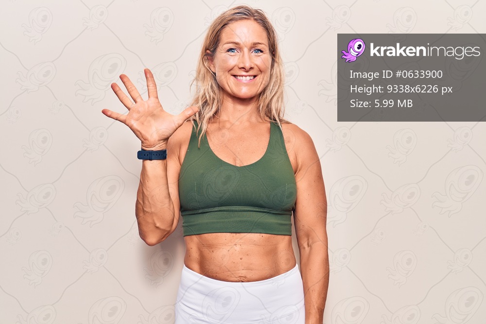 Middle age caucasian blonde woman wearing sportswear showing and pointing up with fingers number five while smiling confident and happy. 