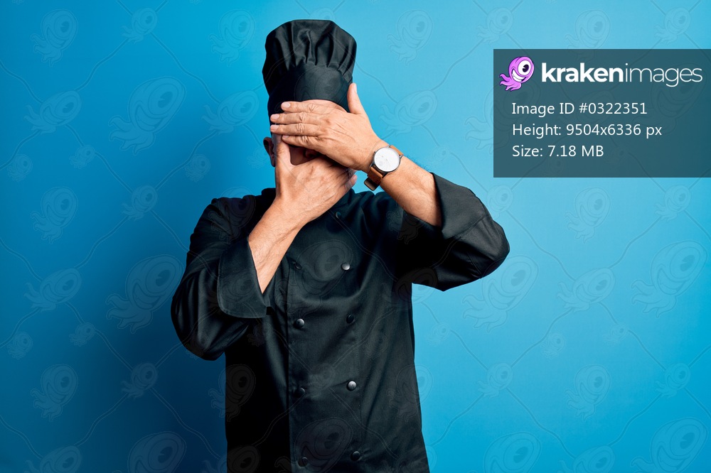 Middle age handsome grey-haired chef man wearing cooker uniform and hat Covering eyes and mouth with hands, surprised and shocked. Hiding emotion