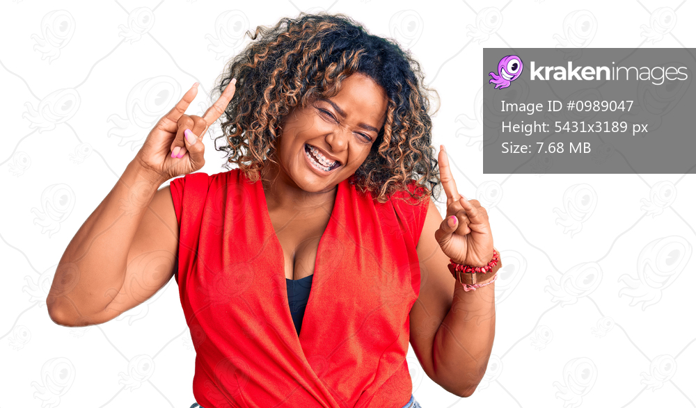 Young african american plus size woman wearing casual style with sleeveless shirt shouting with crazy expression doing rock symbol with hands up. music star. heavy music concept. 