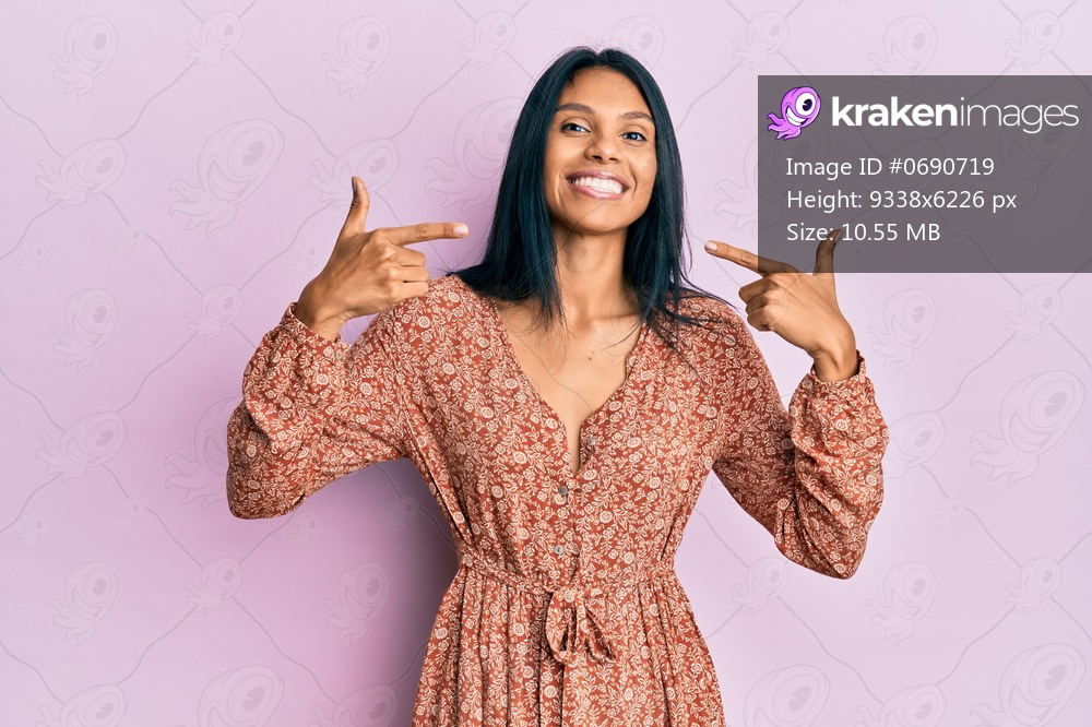 Young african american woman wearing summer dress looking confident with smile on face, pointing oneself with fingers proud and happy. 