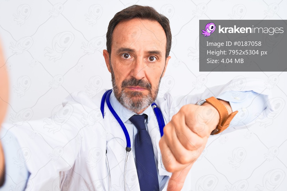 Middle age doctor man wearing stethoscope make selfie over isolated white background with angry face, negative sign showing dislike with thumbs down, rejection concept