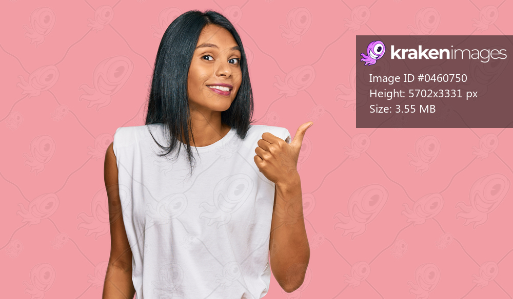 Young african american woman wearing casual clothes smiling with happy face looking and pointing to the side with thumb up. 