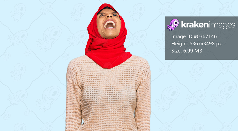 Young african american woman wearing traditional islamic hijab scarf angry and mad screaming frustrated and furious, shouting with anger. rage and aggressive concept. 